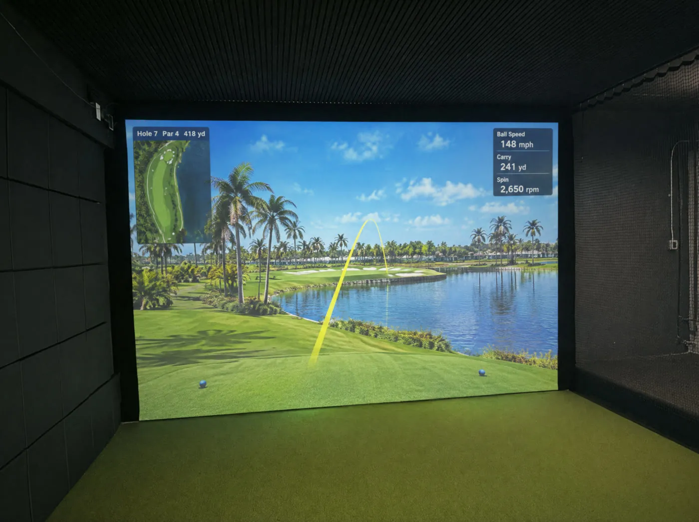 180-inch impact screen showing a golf hole with shot data