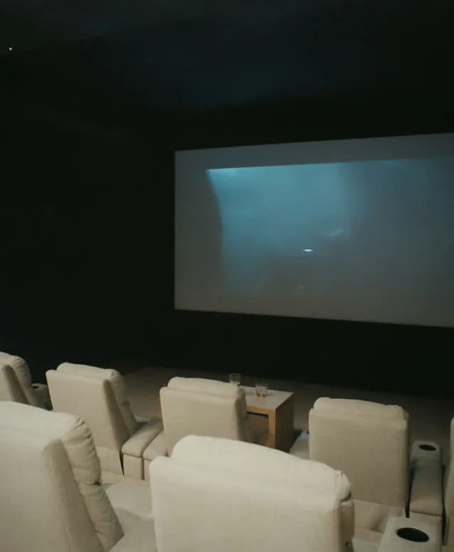 Dedicated home theater with a projection screen and rows of white recliners
