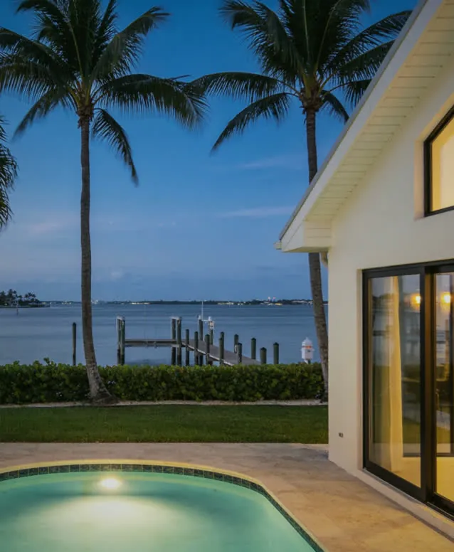 Waterfront house on Sarasota Bay at dusk, pool lit beside the lanai doors